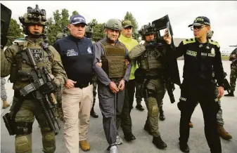  ?? Colombian Presidenti­al Press Office ?? Police escort Dairo Antonio Usuga (center), the alleged leader of the Clan del Golfo drug cartel. before his extraditio­n to the United States at a military airport in Bogota, Colombia.