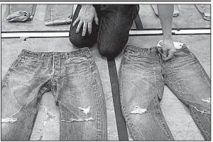  ?? AP ?? Bart Sights, head of Levi Strauss &amp; Co.’s Eureka Innovation Lab, compares the markings and damage on jeans he guesses are close to 30 years old (left) to jeans made within a few hours of this photograph.