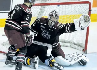  ?? CLIFFORD SKARSTEDT/EXAMINER ?? Peterborou­gh Petes goalie Dylan Wells makes a glove save with a Kingston Frontenacs player in his net next to Brandon Prophet during third period of Game 1 Eastern Conference Semifinal OHL action on Thursday night at the Memorial Centre in...