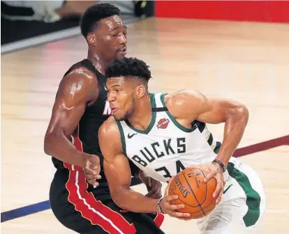  ?? KIM KLEMENT-POOL/GETTY ?? Bucks forward Giannis Antetokoun­mpo, right, moves to the basket against Heat forward Bam Adebayo during the first half of a game Thursday at The Arena at ESPN Wide World Of Sports Complex in Lake Buena Vista, Florida.