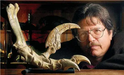  ?? Deseret News/AP ?? ■ State paleontolo­gist James L. Kirkland looks at a reconstruc­ted foot of a Utahraptor dating back 125 million years ago at the Utah Division of Natural Resources office in Salt Lake City.