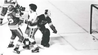  ?? FILES ?? Rick Blight, centre, ties up Blues’ defenceman Barry Gibbs while the St. Louis goalie helplessly looks at the puck rolling toward the net in a 1978 game in Vancouver. Blight had 63 points for Vancouver that season.