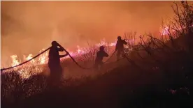  ?? ?? A volunteer with the Greek fire service tackles a wildfire in near Athens. Photograph: Courtesy of Babis Zacharis