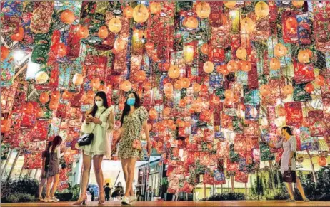  ?? AFP ?? People walk under festive decoration­s for the upcoming Lunar New Year outside a shopping mall in Bangkok, Thailand.