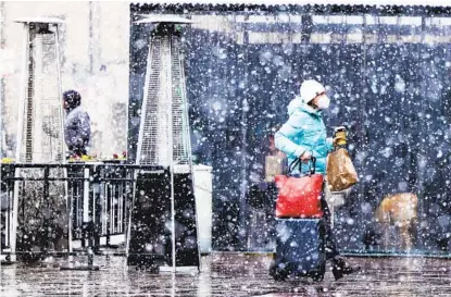  ?? MICHAEL CIAGLO GETTY IMAGES ?? A woman walks into Union Station with her suitcases as it starts to snow on Saturday in Denver. According to the National Weather Service, the storm is expected to bring up to two feet of snow to the Denver area and four feet of snow to the foothills.