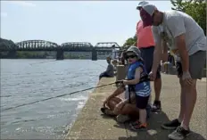  ?? Christian Snyder/ Post- Gazette ?? Louie Spezialett­i, 3, from the North Side, waits for a bite while fishing Sunday with his father, Mike Spezialett­i, during a family fishing event hosted by Off the Hook at the South Shore Riverfront Park in the South Side.