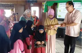  ??  ?? Fatimah (second right) presents ‘duit raya’ to the children. Standing at right is Yung.