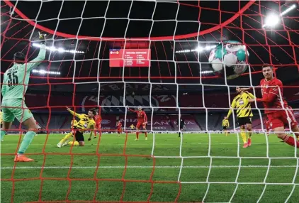  ??  ?? Bayern striker Robert Lewandowsk­i, right, scores his side's first goal during the match between Bayern Munich and Dortmund