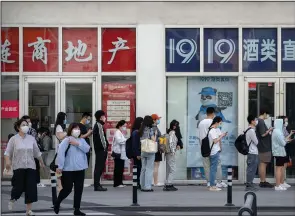  ?? (AP/Mark Schiefelbe­in) ?? Employees wearing face masks wait to have their covid-19 test results checked to enter an office building Tuesday in the central business district in Beijing.