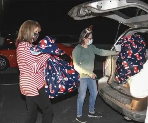  ?? The Sentinel-Record/Grace Brown ?? PRESENTS: Brandi Cannon, left, and Amy Tinsley load bags of toys into a vehicle last Thursday at the Miracle on McAuley Court Christmas Program Distributi­on Night at Lake Valley Community Church, 910 Shady Grove Road. The event is sponsored by the Cooper-Anthony Mercy Child Advocacy Center.