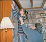  ??  ?? Volunteers Angelina Bartorelli, of Dublin, and Bonnie Janke, of Lower Gwynedd, help tape plastic over books in the library.