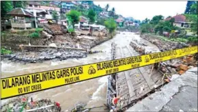  ?? RANGGA FIRMANSYAH/AFP ?? A police line is placed at a damaged bridge following torrential rain in Bogor, West Java, Indonesia, on April 28.