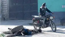  ?? AFP ?? STOP AND STARE
A man on a motorcycle looks at a corpse near the National Penitentia­ry in Haiti’s capital Port-au-Prince on Sunday, March 3, 2024. TELEVISION SCREENGRAB