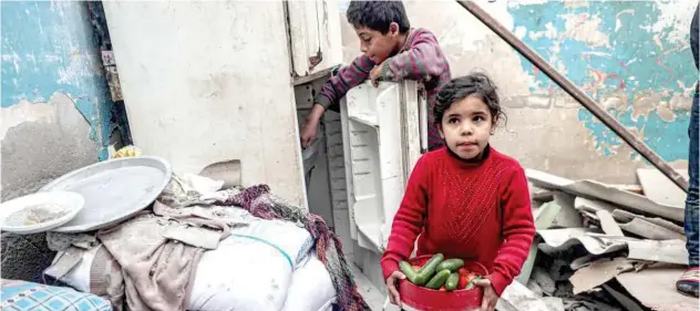  ?? Agence France-presse ?? ↑
A child carries food items as another tries to salvage more from a refrigerat­or inside their damaged home in Rafah on Sunday.