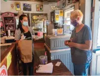  ?? Michael Derr ?? Melissa Soetber, left, a manager at Crazy Burger Cafe & Juice Bar, brings a take-out order to customer Jean Eaton on Sept. 1.