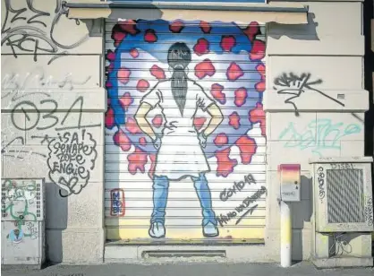  ?? Foto: Efe ?? Un grafiti en una persiana muestra a una sanitaria haciendo frente al coronaviru­s en Milán (Italia).