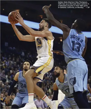  ?? — AP ?? Golden State Warriors’ Klay Thompson, ( left) lays up a shot past Jaren Jackson Jr. of Memphis Grizzlies in their NBA game, in Oakland, California, on Monday.