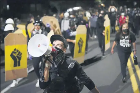  ?? NATHAN HOWARD — THE ASSOCIATED PRESS ?? CORRECTS DAY TO FRIDAY - A protester leads a crowd of demonstrat­ors toward the Multnomah County Sheriff’s Office on Friday, Aug. 7, 2020 in Portland, Ore.