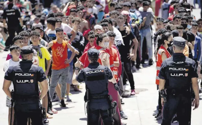  ?? José Luis Roca ?? Policías controlan a un grupo de menores mientras la Cruz Roja los atiende, ayer en Ceuta.