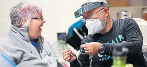  ?? R.J. JOHNSTON TORONTO STAR ?? At the Repair Café under the North Market tent on The Esplanade, customer Naomi Tyrrell sits with volunteer Ken Vickerson, who fixes her broken bracelet.