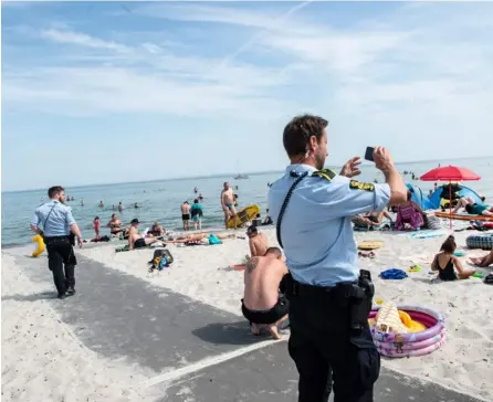  ?? AFP ?? Agentes de la Policía vigilaban ayer si los bañistas mantenían la distancia en la playa de Saksild Strand, cerca de Odder, Finlandia.