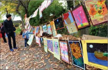  ?? TANIA BARRICKLO — DAILY FREEMAN ?? Dov Badinter-Camuzeaux of Kingston follows his son Micah, 6, a new student at George Washington Elementary School, along the presentati­on of artwork done by Kingston elementary school children on Saturday. The two were visiting the 7th Annual Festival of Scarecrows held at the Louw-Bogardus house ruins on Frog Alley in Uptown Kingston.