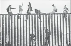  ?? SANDY HUFFAKER/GETTY-AFP ?? Migrants protest Sunday on the border fence in San Ysidro, Calif., as nearly 200 Central Americans sought to apply for protection at the nation’s busiest border crossing.