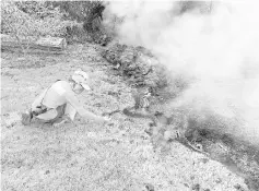  ?? — Reuters photo ?? An HVO geologist collects samples of spatter by fissure 10 from the Kilauea volcano, in the Leilani Estates.