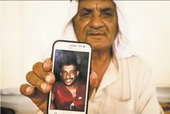  ?? Maya Alleruzzo / Associated Press ?? Jassim Mohammed Ibrahim shows a picture of his son, Ali Thamin Jassim Mohammed Ibrahim, who was arrested by Iraqi security forces. Ibrahim does not know where his son is being held.