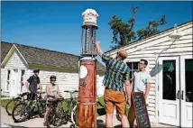  ??  ?? Visitors inspect an old gas pump in Glen Haven, a preserved 19thcentur­y port town where steamers stopped for food, lodging and wood, in Sleeping Bear Dunes National Lakeshore.