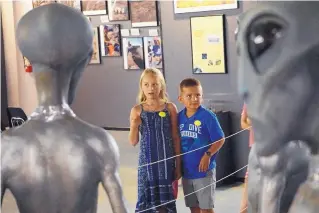  ??  ?? Hanna Stegman, 9, and her brother, Landon Stegman, 5, of Carlsbad, are wide-eyed as they check out a display of alien figures at the Internatio­nal UFO Museum in Roswell.