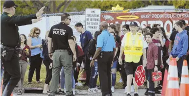  ?? AP PHOTOS ?? BACK TO SCHOOL: A heavy police presence, above and below, greeted returning students at Marjory Stoneman Douglas High School in Parkland, Fla., yesterday.