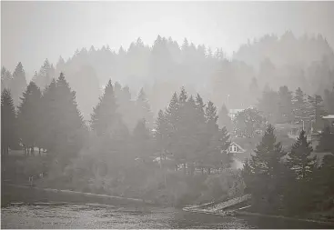  ?? Randy L. Rasmussen / Associated Press ?? Cascade Locks, Ore., nestled in fir trees alongside the Columbia River, is inundated by smoke from a nearby wildfire Wednesday. The blaze was one of dozens of wildfires that sent smoke into cities from Seattle to Denver.