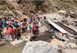  ??  ?? SHIMLA: Indian rescue personnel and volunteers stand amidst wreckage and victims after a bus accident, at the bottom of a ravine near the River Tons at Chopal, some 115kms north of Shimla. —AFP