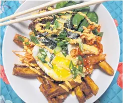  ??  ?? Korean street fries will be a staple on the Saucy Mouth menu. The dish features fresh carrot and cucumber, homemade Newfoundla­nd kimchi, and a fried egg atop a bed of sweet potato fries.