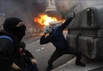  ?? Bernat Armangue/Associated Press ?? A protester uses a sling shot Friday during clashes with police in Barcelona, Spain.