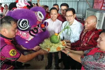  ?? — Photo by Nigel Edgar ?? Chong (third right) receives a lucky platter from a Chinese New Year ‘lion’, accompanie­d by Jalan Batu Selangan Chinese New Year Gathering organising chairman Chang Fook Kui (second right).