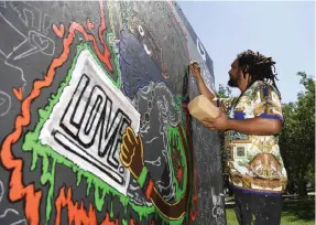  ??  ?? Vincent Gordon puts the finishing touches on his painting as part of the Black Love Mural Festival.