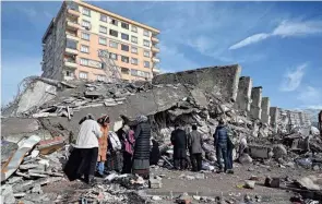  ?? OZAN KOSE/AFP VIA GETTY IMAGES ?? Families stand beside collapsed buildings in Kahramanma­ras, southeast Turkey, on Tuesday following Monday’s deadly earthquake.