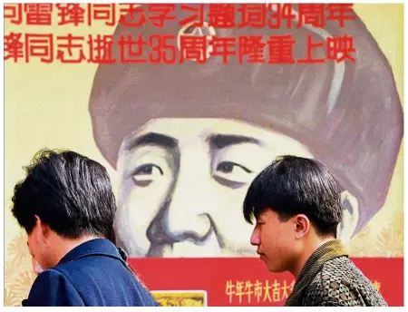  ?? — AP ?? Rememberin­g a patriot: People standing in front of a poster of Lei Feng in this file picture. KFC in China launched its first ‘Lei Feng Spirit’ restaurant on Tuesday, the official remembranc­e day for the soldier.