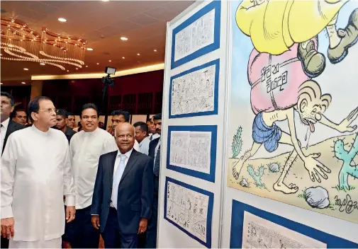  ??  ?? President Sirisena, who has been sharply critical of the media in recent weeks, looking at a giant Gajaman cartoon at an exhibition held to mark the 50th anniversar­y of veteran cartoonist Camillus Perera and his character Gajaman.