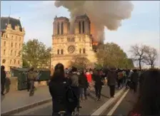  ?? Photos by Loretto O’ Sullivan. ?? Parisians and tourists watch as the fire engulfs the historic Notre Dame cathedral on Monday evening.