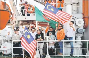  ??  ?? Volunteers of the Malaysian aid ship Nautical Aliya waving flags as they anchored to Chittagong Container Terminal with relief for Rohingya refugees in Chittagong, Bangladesh. — Reuters photo