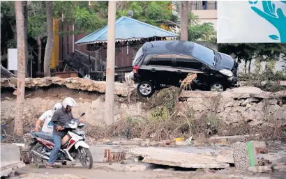  ?? AFP ?? A man attempts to ride his motorcycle through the mud in Palu in Central Sulawesi on Saturday. —