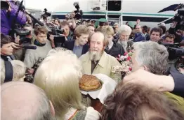  ?? — AFP ?? A file photo shows Russian writer Alexander Solzhenits­yn ( centre) receiving a loaf of traditiona­l Russian bread after arriving at Vladivosto­k airport, following 20 years of exile.