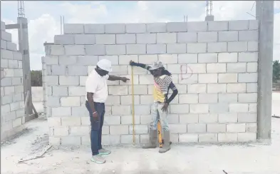  ?? ?? Quality Control Manager Akanni Blair (left) and a worker double checking the specificat­ions on site