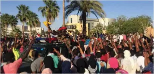  ?? (Reuters) ?? SUDANESE DEMONSTRAT­ORS flash the victory sign as a military police vehicle drives past them during a protest in Khartoum Saturday, demanding Sudanese President Omar Al-Bashir step down.