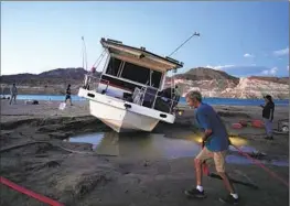  ?? John Locher Associated Press ?? CRAIG MILLER hauls a hose while trying to free his stranded houseboat at Lake Mead National Recreation Area last June. The water level has since risen.