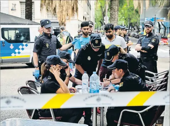  ?? ÀLEX GARCIA ?? Policías nacionales comprueban la documentac­ión de dos detenidos en una oficina improvisad­a en una terraza de la Rambla del Raval