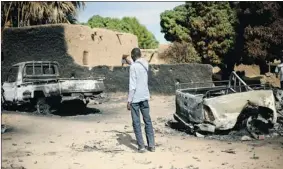  ?? JÉRÔME DELAY/ THE ASSOCIATED PRESS ?? A man takes a picture of the charred remains of trucks used by radical Islamists in Diabaly, Mali, on Monday. Many residents fled on foot through rice fields.